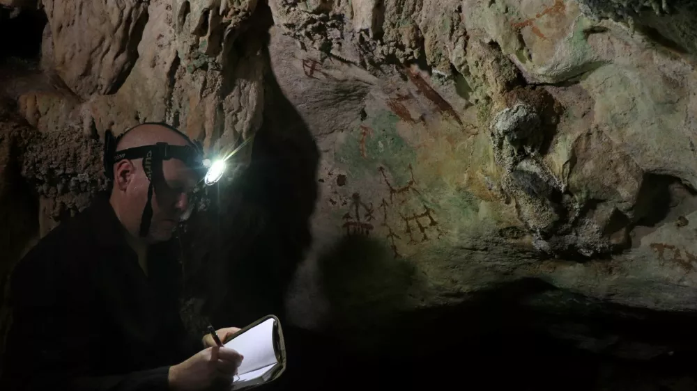 Researcher Maxime Aubert examines an ancient cave painting in a limestone cave called Liang Metanduno on Muna, a small satellite island off the southeastern peninsula of the Indonesian island of Sulawesi, in this photograph released on January 21, 2026. Ahdi Agus Oktaviana/Handout via REUTERS  THIS IMAGE HAS BEEN SUPPLIED BY A THIRD PARTY. NO RESALES. NO ARCHIVES.