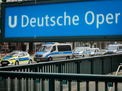 24 January 2026, Berlin: Police vehicles are parked near the entrance to the Deutsche Oper subway station. A teenager suffered a fatal electric shock in a Berlin subway station when he tried to retrieve his fallen e-cigarette from the track bed. Photo: Christoph Soeder/dpa
