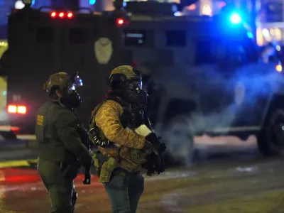 Federal agents stand guard as they try to clear the demonstrators near a hotel, using tear gas during a noise demonstration protest in response to federal immigration enforcement operations in the city Sunday, Jan. 25, 2026, in Minneapolis. (AP Photo/Adam Gray)