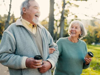 Senior couple, park and morning walk with conversation, love and bonding together with health. Wellness, marriage and retirement with outdoor, communication and coffee on urban garden path on date