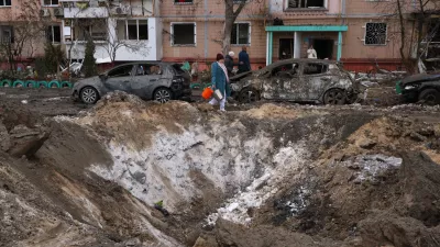 People pass a crater and damaged cars near an apartment building after a Russian attack in Zaporizhzhia, Ukraine, Wednesday, Jan. 28, 2026. (AP Photo/Kateryna Klochko)