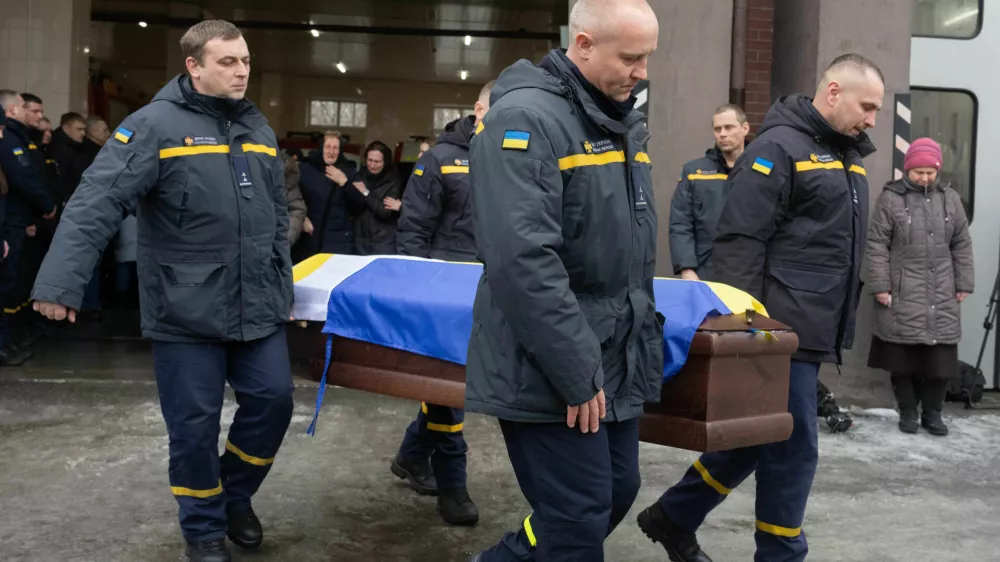Rescuers carry the coffin of their fellow Oleksandr Zibrov, 36, who was killed in a secondary Russian drone strike on a residential building, at a fire station in Kyiv, Ukraine, Wednesday, Jan. 28, 2026. (AP Photo/Efrem Lukatsky)