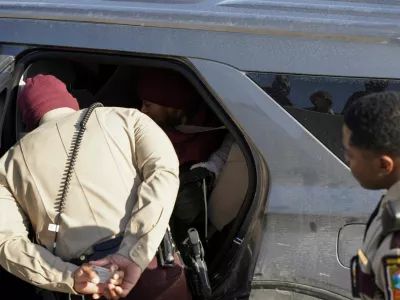 A Minnesota state policeman speaks to a woman sitting inside an ICE vehicle after she was briefly detained on Interstate 35W by Federal immigration agents while they conduct immigration enforcement tasks in Minneapolis, Minnesota, U.S., February 3, 2026. REUTERS/Seth Herald