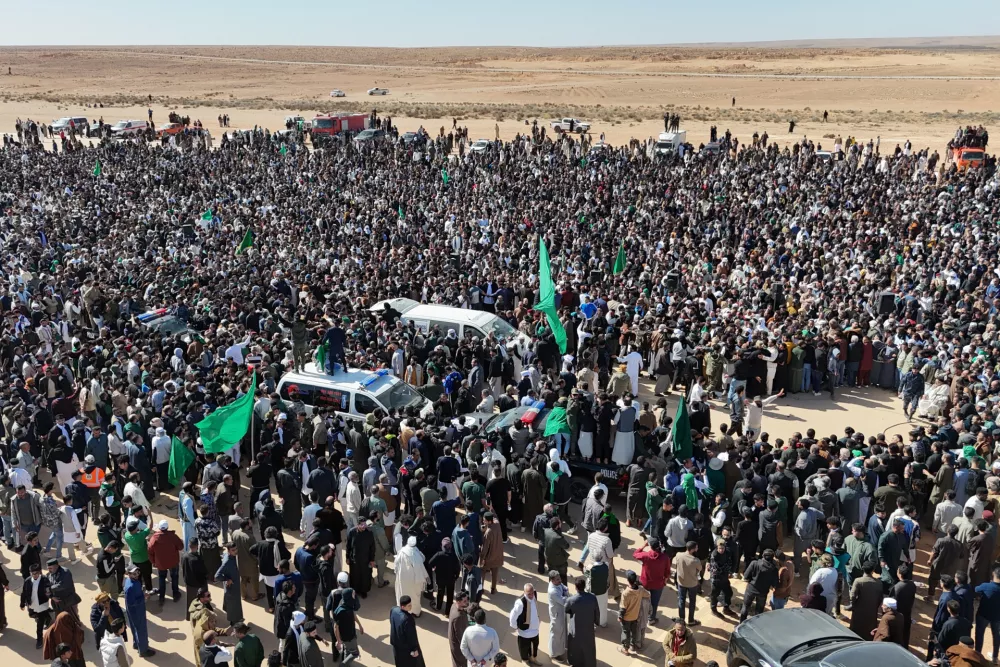 Thousands of Libyans crowd to attend the funeral of Seif al-Islam, son of former Libyan Leader Moammar Gadhafi, as they hold a poster of his father in Bani Walid city, Libya, Friday, Feb. 6, 2026. (AP Photo/Yousef Murad)
