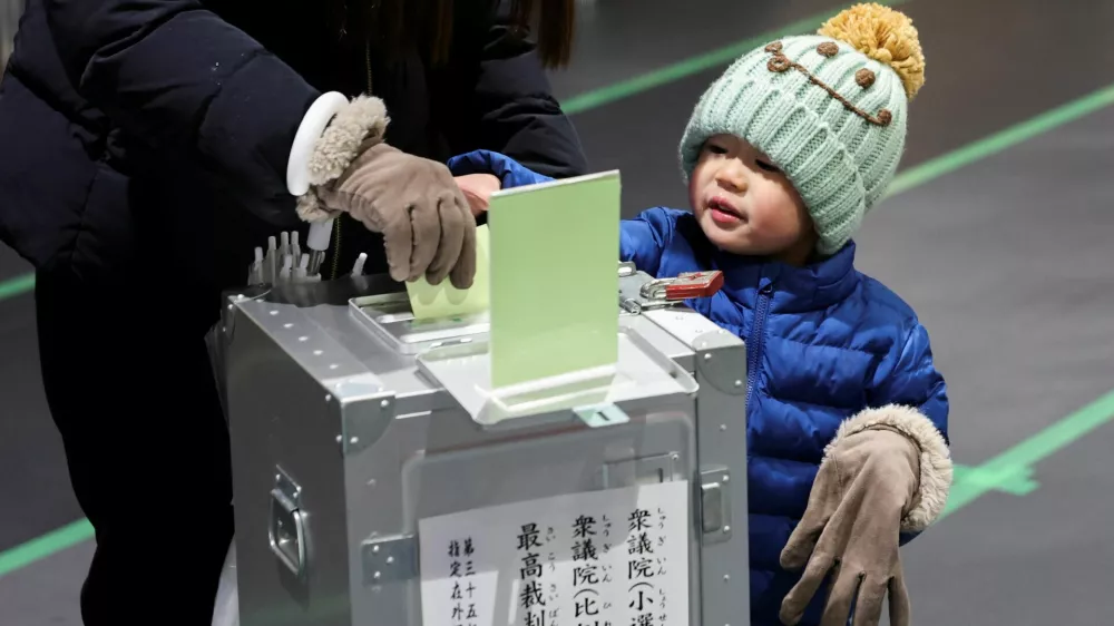 A boy looks on as his mother casts her ballot for a general election at a polling station in Tokyo, Japan, on February 8, 2026. REUTERS/Kim Kyung-Hoon