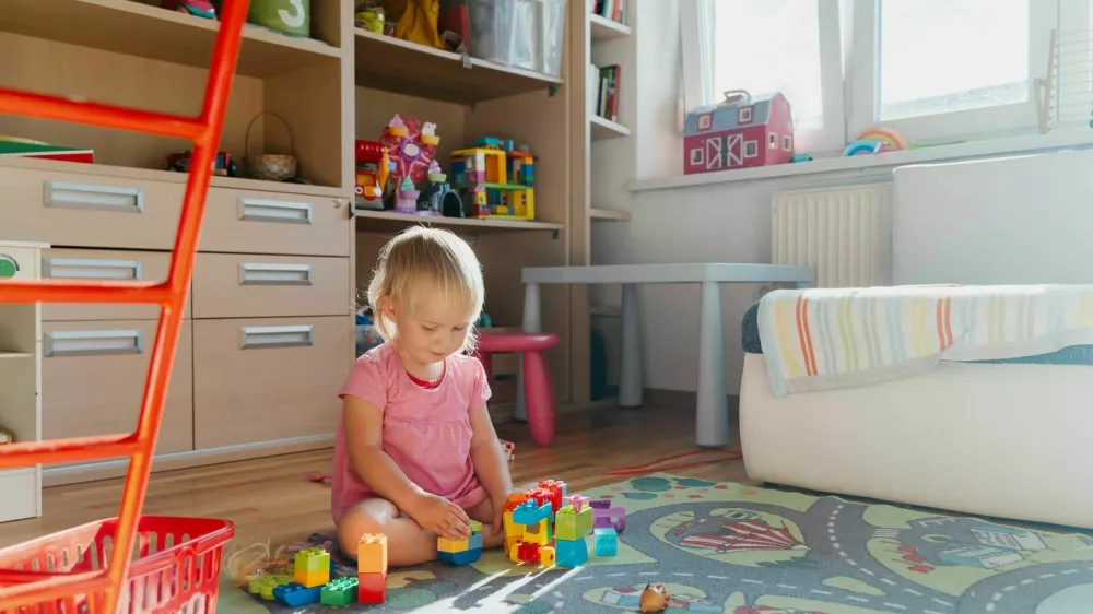 Cute little girl playing with colorful blocks at children's room. Happy childhood. Toddler plays on the floor surrounded by toys. Cute little child play spending time playing at home / Foto: Nataliaderiabina