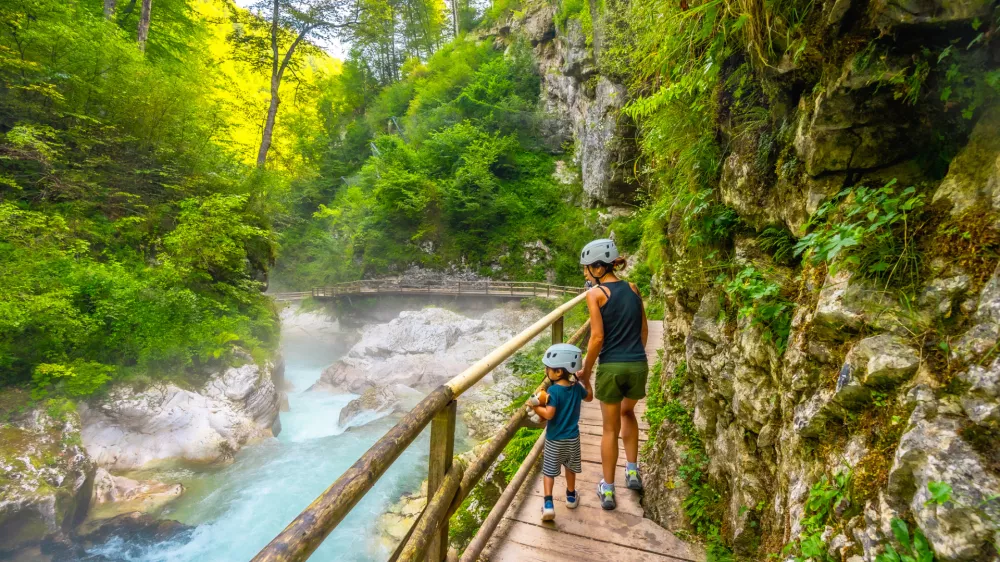 Mother and child walking on wooden path exploring vintgar gorge near bled, enjoying summer vacation in beautiful nature of slovenia