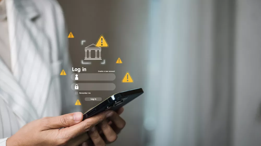 Business professional holding smartphone with bank login screen and yellow warning iconsconcept of mobile banking alert, phishing risk, account security, two-factor authentication, fraud prevention.