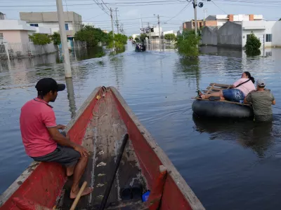 Residents wade through a flooded neighborhood in Monteria, Colombia, Tuesday, Feb. 10, 2026. (AP Photo/Fernando Vergara)