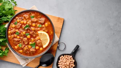 Moroccan Harira Soup in black bowl at grey concrete table top. Harira is Moroccan Cuisine dish with lamb or beef meat, chickpeas, lentils, tomatoes, ciliantro. Ramadan Iftar Food. Copy space. Top view / Foto: Andrei Kravtsov