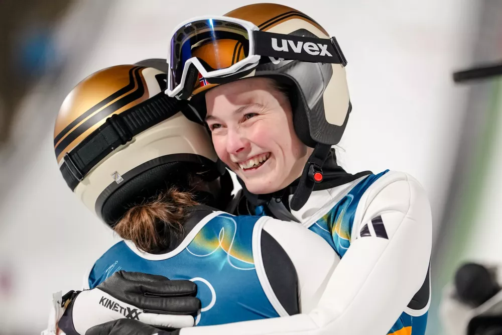 Silje Opseth, of Norway, right, hugs gold medalist Anna Odine Stroem, also of Norway, after the ski jumping women's large hill individual at the 2026 Winter Olympics, in Predazzo, Italy, Sunday, Feb. 15, 2026. (AP Photo/Matthias Schrader)