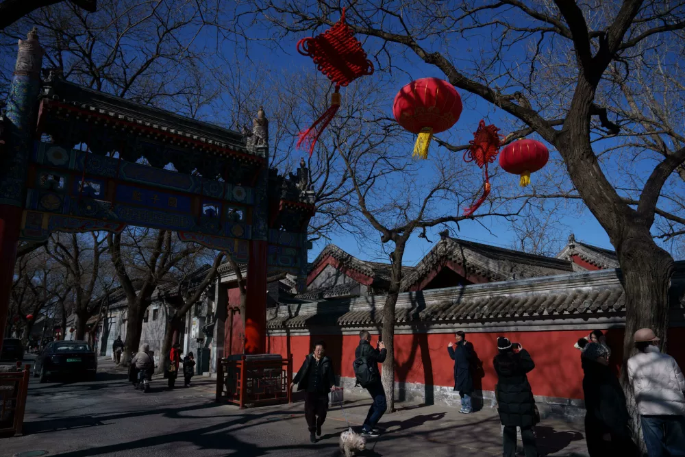 Visitors walk beneath red lanterns hanging at a traditional archway in a hutong neighborhood ahead of Lunar New Year in Beijing, China, Monday, Feb. 16, 2026. (AP Photo/Vincent Thian)