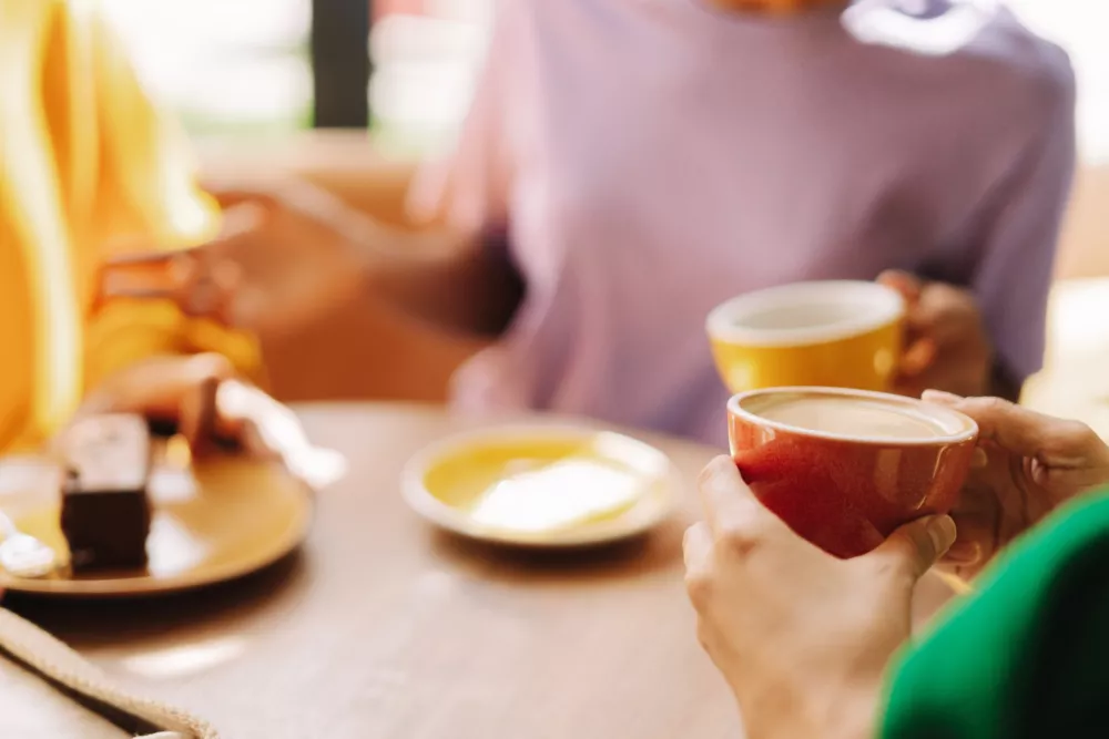 Women talking and enjoying coffee and cake in cafe selective focus, closeup. Coffee break concept / Foto: Mariia Vitkovska