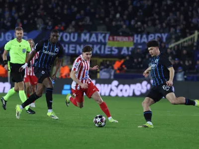 Atletico Madrid's Julian Alvarez, centre, and Brugge's Kyriani Sabbe, right, challenge for the ball during the Champions League play-off first leg soccer match between Club Brugge and Atletico Madrid, in Bruges, Belgium, Wednesday, Feb. 18, 2026. (AP Photo/Omar Havana)