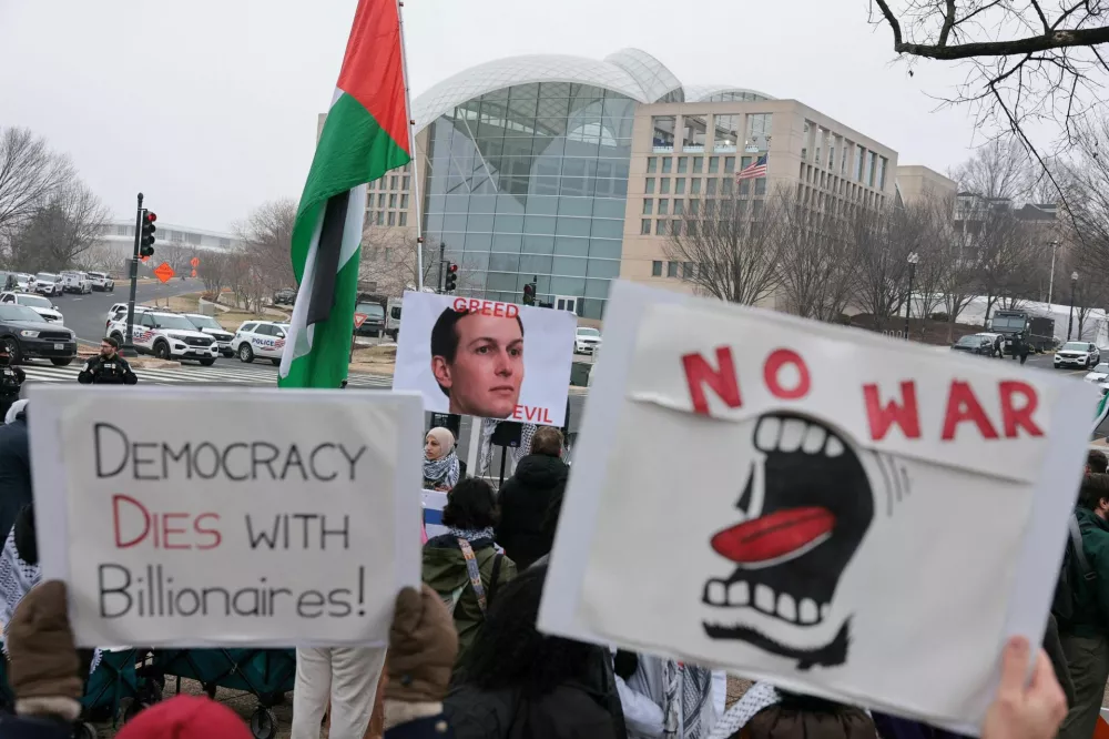 Demonstrators hold signs, near the U.S. Institute of Peace building, during a protest on the day of the inaugural meeting of the Board of Peace, in Washington, D.C., U.S., February 19, 2026. REUTERS/Jonathan Ernst