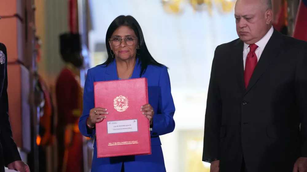 Acting President Delcy Rodriguez holds up an amnesty bill approved by the National Assembly alongside Interior Minister Diosdado Cabello at Miraflores Palace in Caracas, Venezuela, Thursday, Feb. 19, 2026. (AP Photo/Ariana Cubillos)