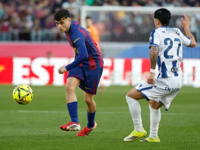 Barcelona's Pedri passes the ball by Levante's Paco Cortes during a La Liga soccer match between Barcelona and Levante in Barcelona, Spain, Sunday, Feb. 22, 2026. (AP Photo/Joan Monfort)