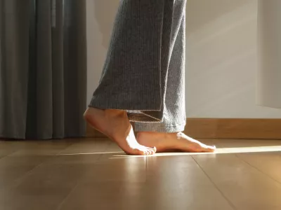 Barefoot woman on the wooden floor. Concept of the underfloor heating in the apartment.