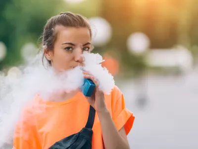 Pretty young girl vape popular ecig gadget,vaping device.Happy brunette vaper girl with e-cig.Portrait of smoker female model with electronic cigarette vaporizer.Ejuice vaping with fruit flavor liquid