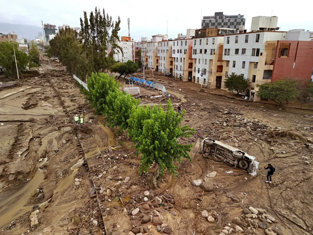 A man takes photos on a destroyed road after heavy rain triggered flooding in Arequipa, Peru, Monday, Feb. 23, 2026. (AP Photo/Jose Sotomayor)