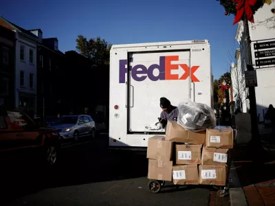 FILE PHOTO: A driver of FedEx stands with packages near a delivery truck during Black Friday preparations in the Georgetown neighborhood of Washington, U.S., November 26, 2024. REUTERS/Benoit Tessier/File Photo