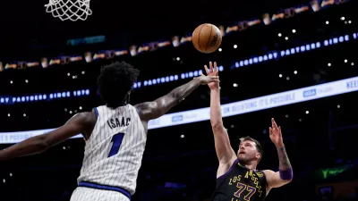 Los Angeles Lakers guard Luka Doncic (77) shoots the ball while being guarded by Orlando Magic forward Jonathan Isaac (1) during the second half of an NBA basketball game Tuesday, Feb. 24, 2026, in Los Angeles. (AP Photo/Caroline Brehman)