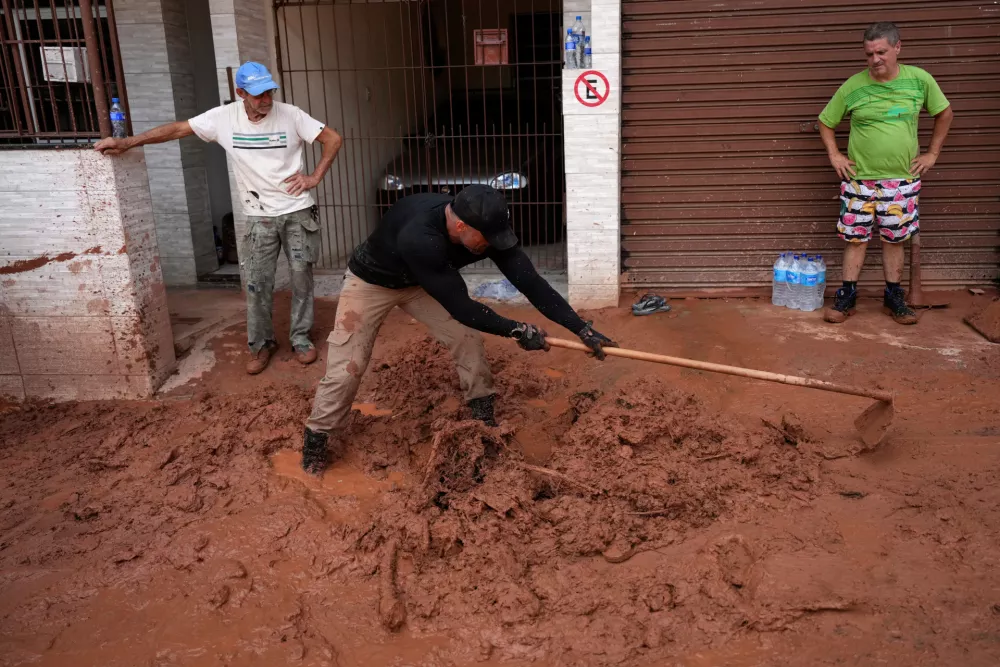 Residents clean up after homes collapsed due to heavy rains and flooding in the Parque Burnier neighborhood of Juiz de Fora, in Minas Gerais state, Brazil, Wednesday, Feb. 25, 2026. (AP Photo/Silvia Izquierdo)