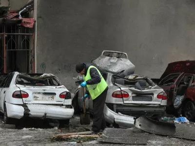 A municipal worker removes debris next to damaged cars outside an apartment building hit by a Russian drone strike on Thursday, amid Russia's attack on Ukraine, in Kharkiv, Ukraine February 26, 2026. REUTERS/Vyacheslav Madiyevskyy