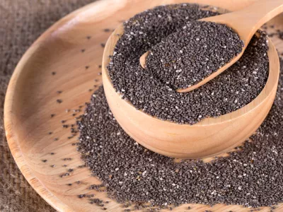 chia seeds in wooden bowl on wooden plate and wooden spoon of chia seeds on top. selective focus. on burlap background.