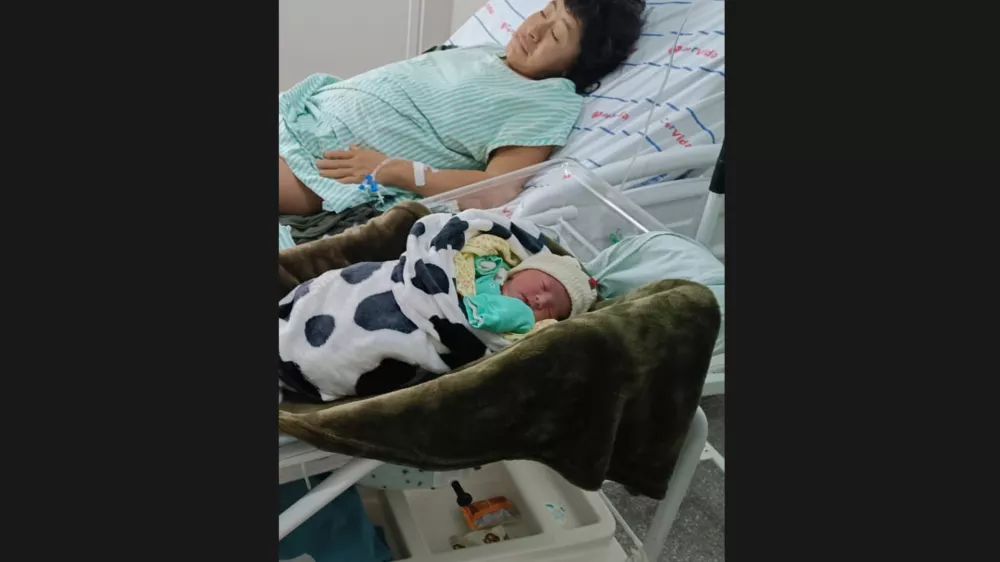 In this photo provided by Funai, Babawru Akuntsu, top, rests beside Akyp, her newborn son, at the Regional Hospital of Vilhena in Vilhena, Rondonia state, Brazil on Dec. 9, 2025, one day after the birth. (Altair Algayer/Funai via AP)