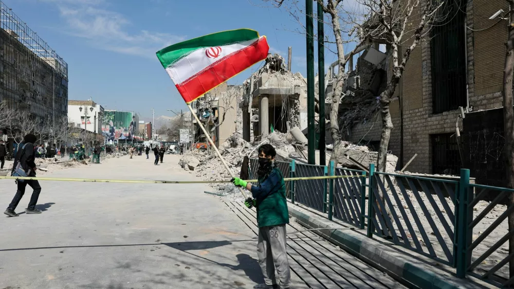 A boy holds an Iranian flag following a strike on a police station, amid the U.S.-Israeli conflict with Iran, in Tehran, Iran, March 4, 2026. Majid Asgaripour/WANA (West Asia News Agency) via REUTERS ATTENTION EDITORS - THIS PICTURE WAS PROVIDED BY A THIRD PARTY / Foto: Majid Asgaripour