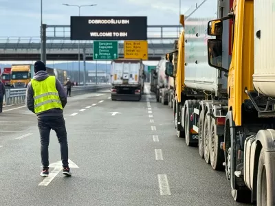 A man stands next to a line of trucks and buses on the Bosnian side of the border with Croatia, in Svilaj, Bosnia, Monday, Jan. 26, 2026, as drivers across the Balkans blocked dozens of border crossings in the region in protest over newly introduced European Union entry regulations.(AP Photo/Eldar Emric)