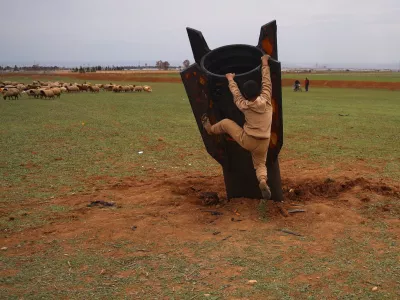 Exposing himself to the danger of unexploded ordnance, a boy tries to climb on an unexploded Iranian projectile that landed in an open field in the outskirts of Qamishli, eastern Syria, Wednesday, March 4, 2026.(AP Photo/Baderkhan Ahmad)