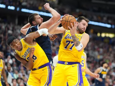 Los Angeles Lakers guard Luka Dončić, right, pulls in a rebound as forward Rui Hachimura, left, boxes out Denver Nuggets center Nikola Jokić in the second half of an NBA basketball game Thursday, March 5, 2026, in Denver. (AP Photo/David Zalubowski)