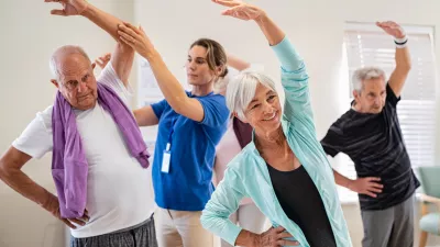 Active seniors doing exercise with physiotherapist at nursing home gym. Trainer helping elderly man and old woman exercising at home. Retired people doing stretching exercises at retirement community.