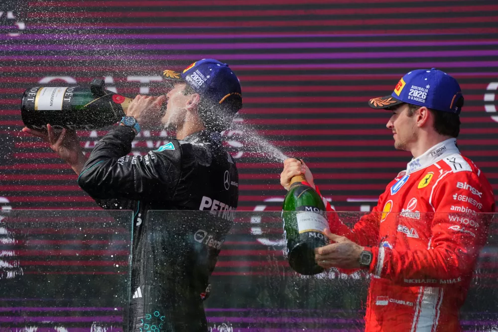 Third placed Ferrari driver Charles Leclerc, right, of Monaco sprays champagne onto race winner Mercedes driver George Russell of Britain on the podium at the Australian Formula One Grand Prix at Albert Park, in Melbourne, Australia, Sunday, March 8, 2026. (AP Photo/Scott Barbour)