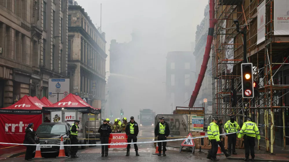 Firefighters damp down the remains of a fire which broke out in a building adjacent to Glasgow Central railway station on Sunday, in Glasgow, Scotland, Monday March 9, 2026. (Robert Perry/PA via AP)