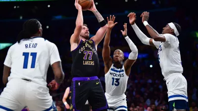 Mar 10, 2026; Los Angeles, California, USA; Los Angeles Lakers guard Luka Doncic (77) shoots against the defense of Minnesota Timberwolves center Naz Reid (11) guard Ayo Dosunmu (13) and forward Jaden McDaniels (3) during the first half at Crypto.com Arena. Mandatory Credit: Gary A. Vasquez-Imagn Images