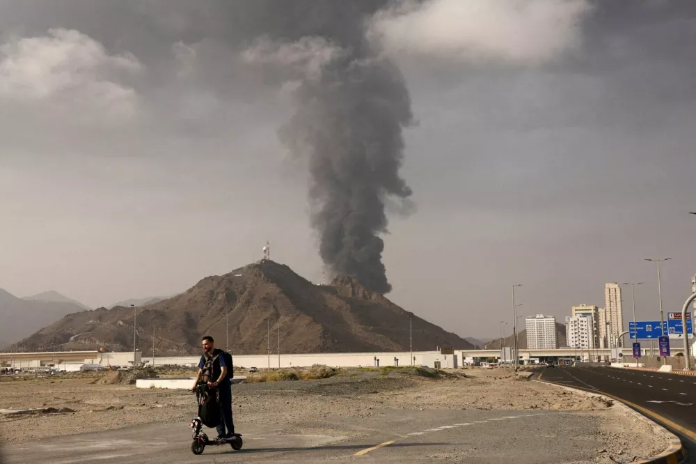 FILE PHOTO: A person rides on a scooter as smoke rises in the Fujairah oil industry zone following a fire caused by debris after interception of a drone by air defenses, in Fujairah, United Arab Emirates, March 3.  REUTERS/Amr Alfiky/File Photo