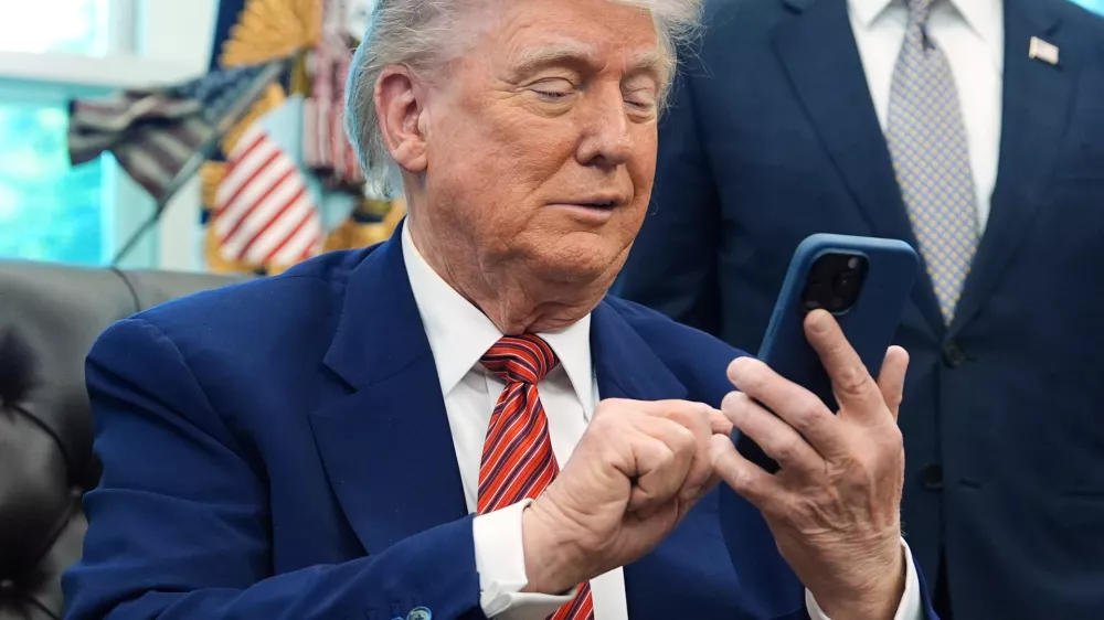 FILE - President Donald Trump silences his mobile phone in the Oval Office of the White House, May 23, 2025, in Washington. (AP Photo/Evan Vucci, File)
