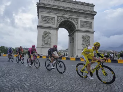 The pack with Slovenia's Tadej Pogacar, wearing the overall leader's yellow jersey, passes the Arc de Triomphe during the twenty-first stage of the Tour de France cycling race over 132.3 kilometers (82.1 miles) with start in Mantes-la-Ville and finish on the Champs-Elysees in Paris, France, Sunday, July 27, 2025. (AP Photo/Mosa'ab Elshamy)