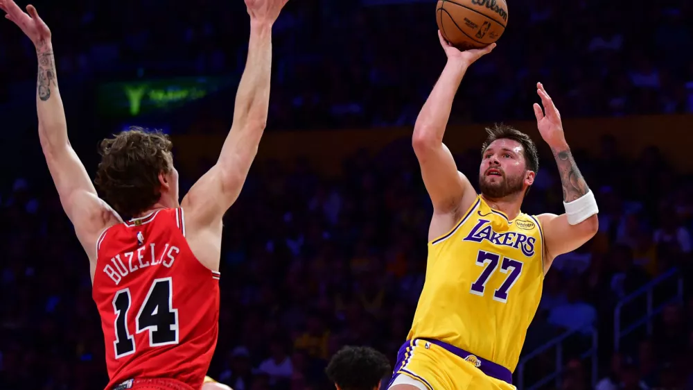Mar 12, 2026; Los Angeles, California, USA; Los Angeles Lakers guard Luka Doncic (77) shoots against Chicago Bulls forward Matas Buzelis (14) during the first half at Crypto.com Arena. Mandatory Credit: Gary A. Vasquez-Imagn Images