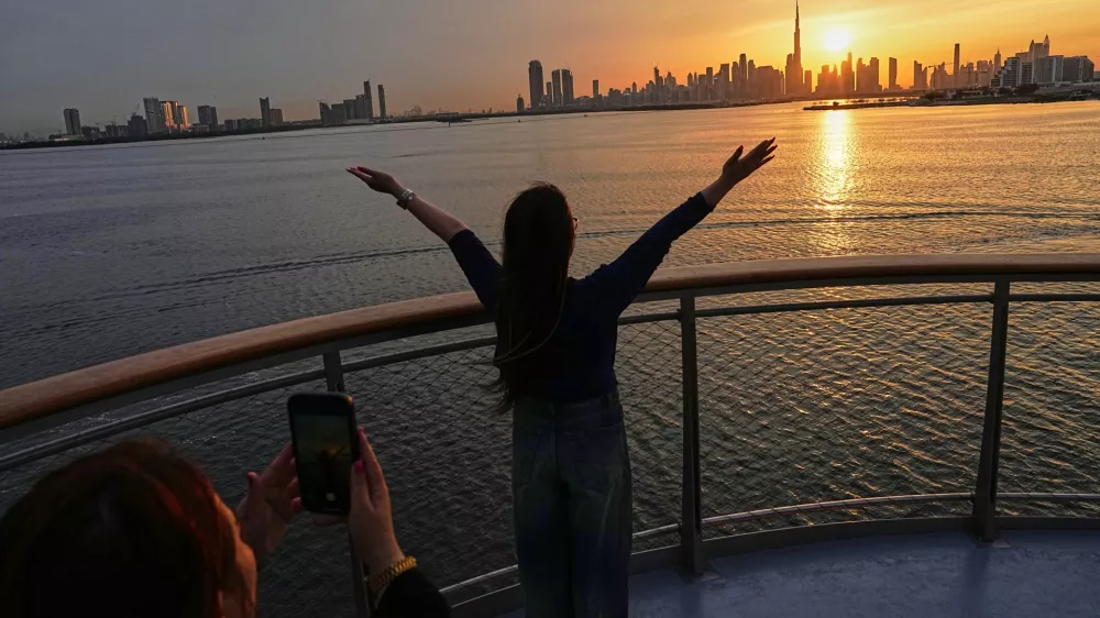Women enjoy the sunset with the view of the city skyline and Burj Khalifa, at Dubai Creek Harbour in Dubai, United Arab Emirates, Wednesday, March 11, 2026. (AP Photo/Fatima Shbair)