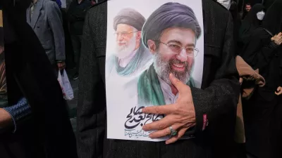 A mourner holds a poster depicting Ayatollah Mojtaba Khamenei, right, the successor to his late father Ayatollah Ali Khamenei, left, as supreme leader, during the funeral procession for senior Iranian military officials and civilians killed during the U.S.-Israel campaign in Tehran, Iran, Wednesday, March 11, 2026. (AP Photo/Vahid Salemi)