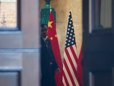 A man stands next to U.S. and China flags at Lancaster House, on the second day scheduled for trade talks between the U.S. and China, in London, Britain, June 10, 2025. REUTERS/Toby Melville