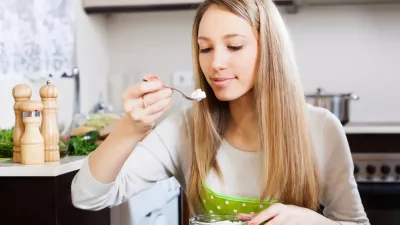 Blonde woman eating curd cheese in home kitchen / Foto: Jackf