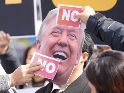 Protesters attach stickers on an image of U.S. President Donald Trump to protest against Trump's demands to multiple countries to send warships to keep the Strait of Hormuz open, near the U.S. Embassy in Seoul, South Korea, Monday, March 16, 2026. (AP Photo/Lee Jin-man)