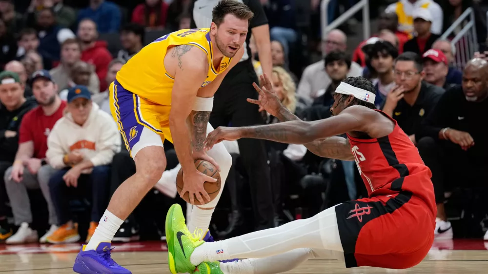 Houston Rockets' Tari Eason, right, falls while guarding Los Angeles Lakers' Luka Doncic during the first half of an NBA basketball game Monday, March 16, 2026, in Houston. (AP Photo/David J. Phillip)