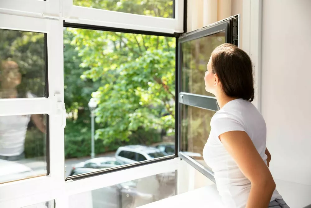 Side View Of A Woman Looking Through Window At Home / Foto: Andreypopov