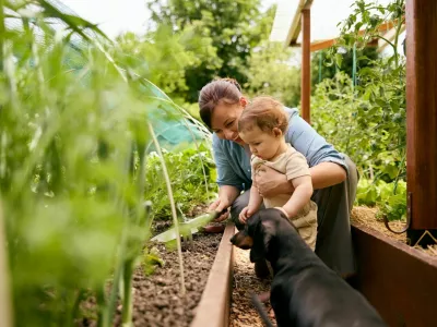A mother and child explore an organic garden, embracing nature and agrotechnology in a green greenhouse. / Foto: Alextn